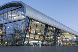 Modernes Gebäude mit geschwungener Glasfassade und innovativem Architekturdesign bei Abenddämmerung