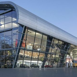 Modernes Gebäude mit geschwungener Glasfassade und innovativem Architekturdesign bei Abenddämmerung