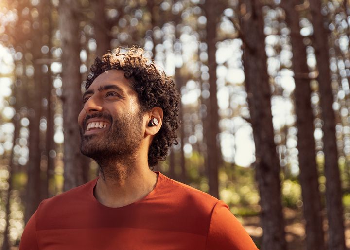 Man smiling in forest and listening to music with Philips sports headphones