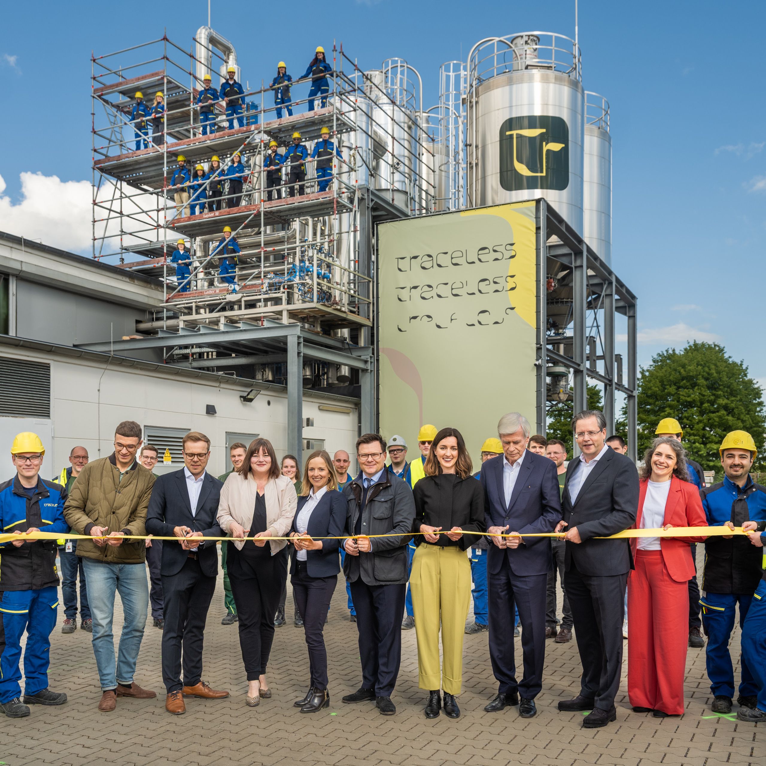 In May 2026, the bioeconomy scale-up Traceless opened its first large-scale production facility in Hamburg-Harburg. Traceless joined the BMW Foundation's RESPOND startup accelerator and it's scaleup pilot. A group of people stand outside a facility, holding a ribbon. Workers in blue uniforms are on scaffolding beside a large industrial structure.