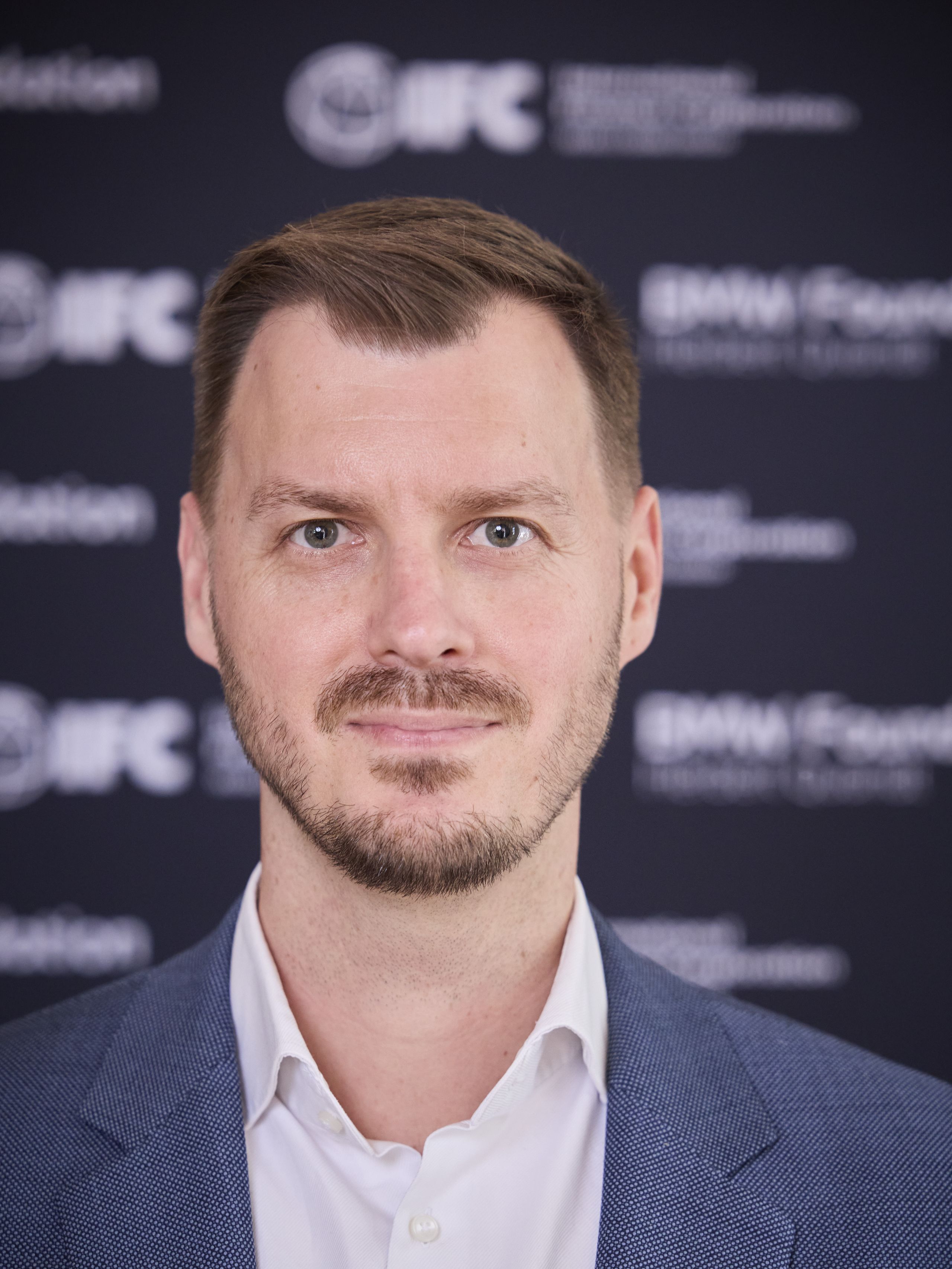 Tim Bölken, CEO of Ineratec. A man in a blue suit and white shirt is standing in front of a dark background with logos.
