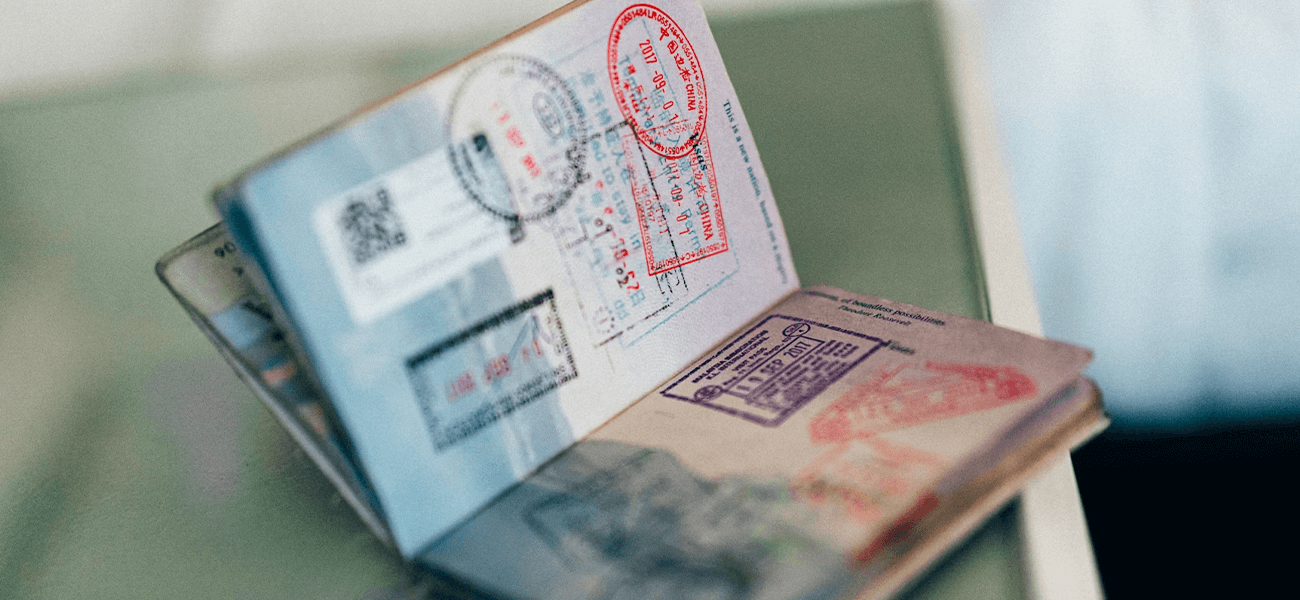 Open passport showing various stamps on its pages, placed on a reflective surface.