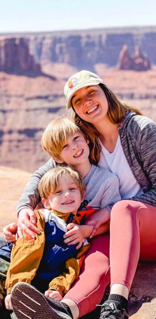 Au pair sitting in front of a view with two host family children.