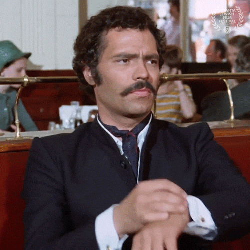 GIF of a man with an impressive moustache looking down at his watch