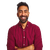 A smiling man with a beard and short dark hair, wearing a maroon button-up shirt, stands with his arms crossed.