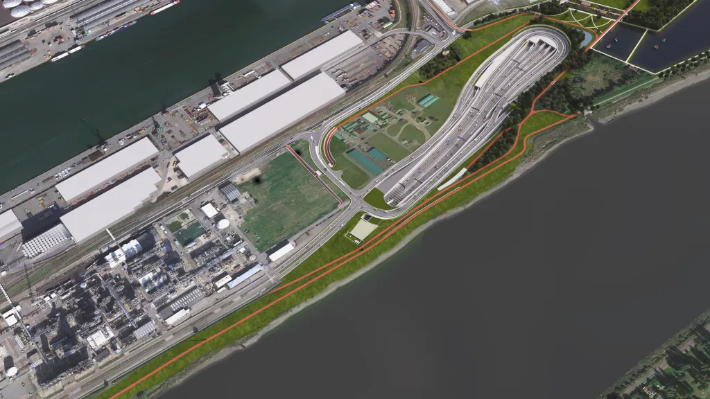 Aerial view of a waterfront area with industrial buildings, roads, greenery, and a large curved bridge near the water's edge.