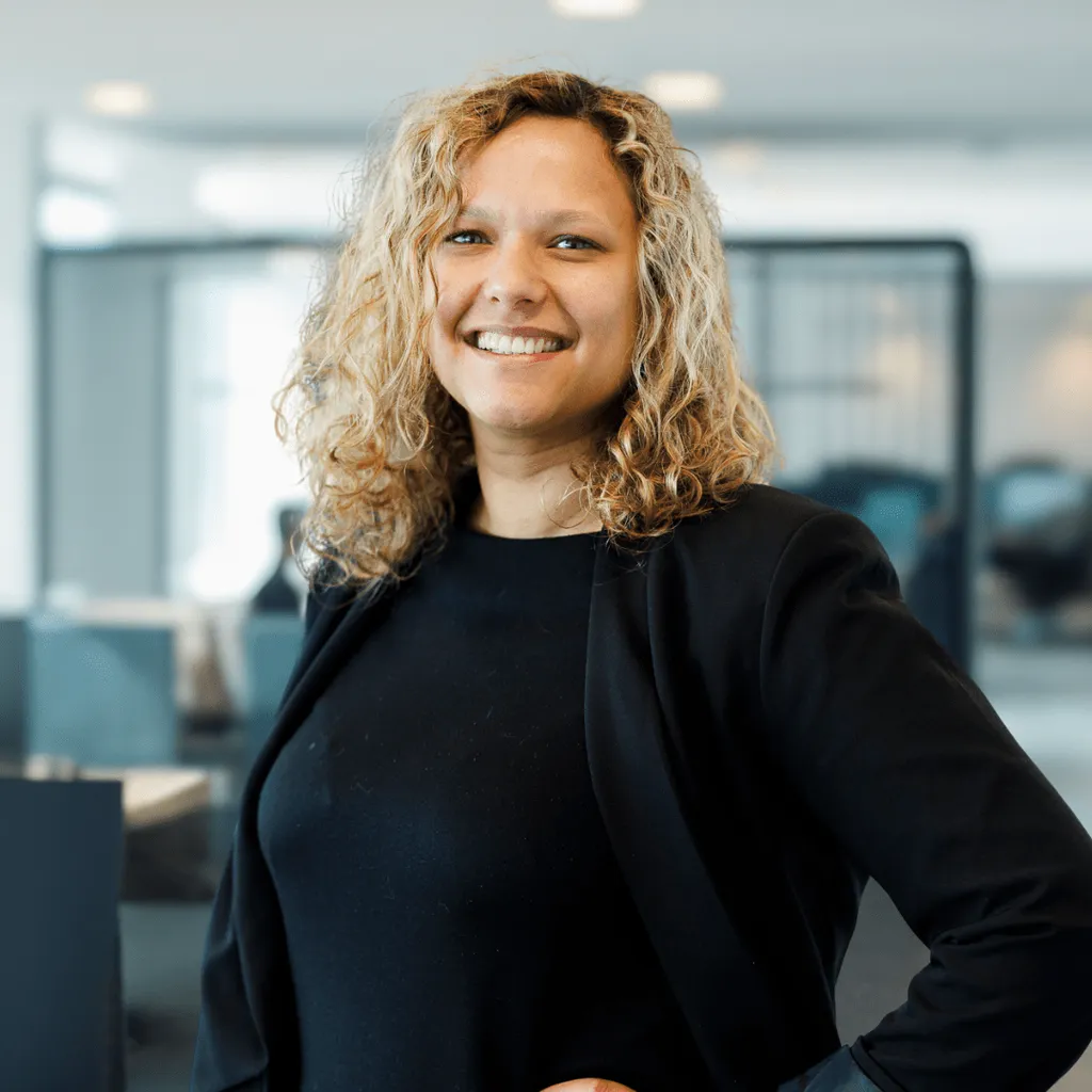 A woman with curly hair smiles, showcasing her vibrant personality and confidence.
