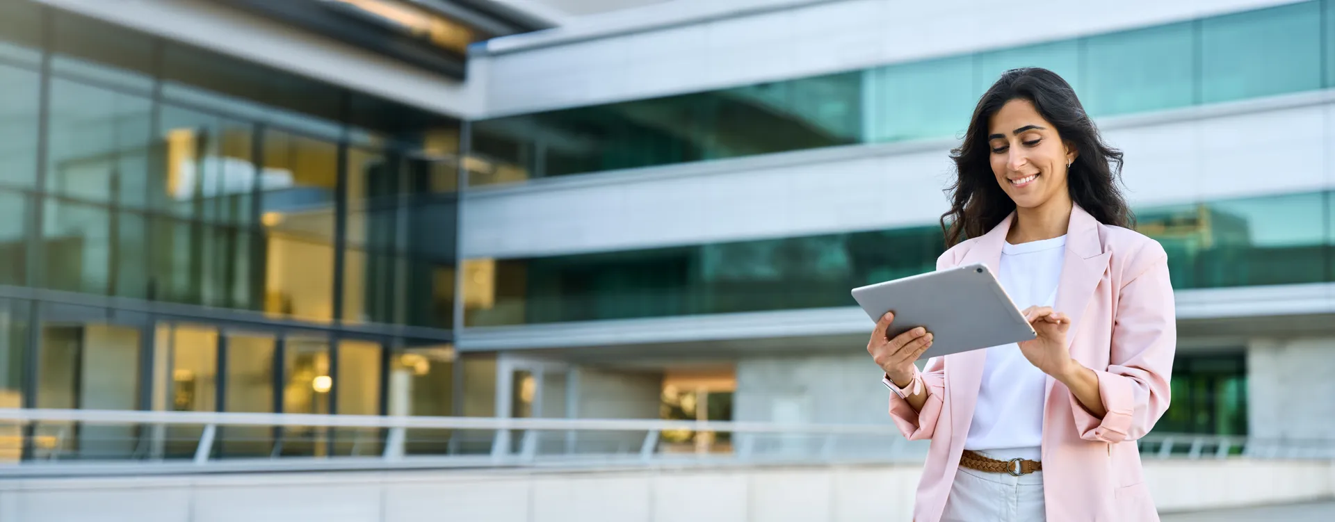 Een vrouw houdt een Ipad vast en lacht naar het apparaat.