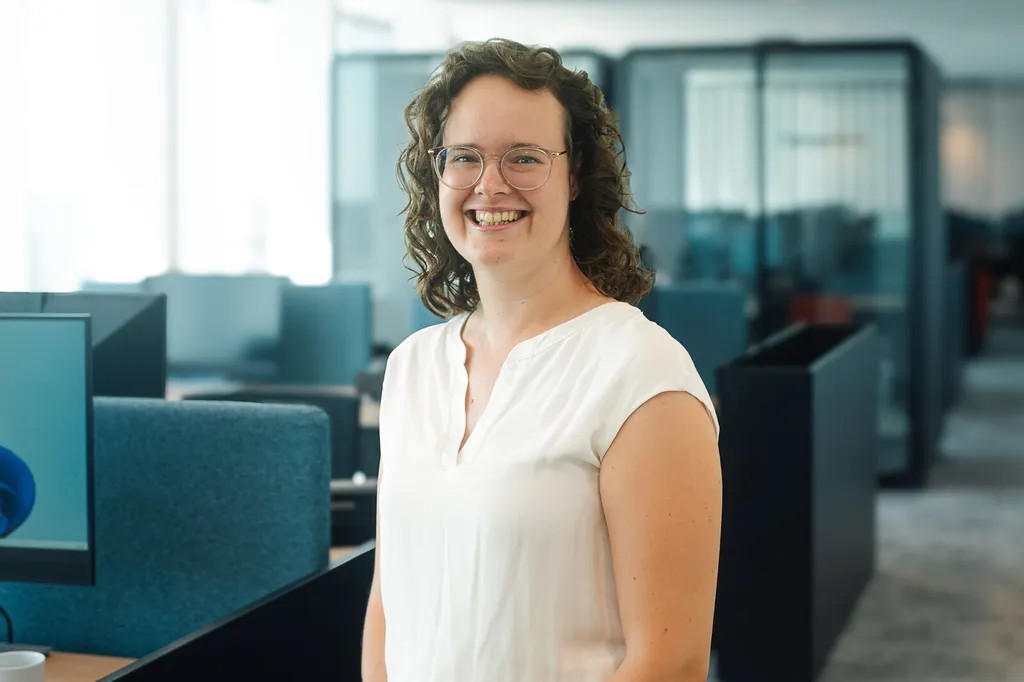headshot of Jenifer our female colleague smiling with glasses on in an office