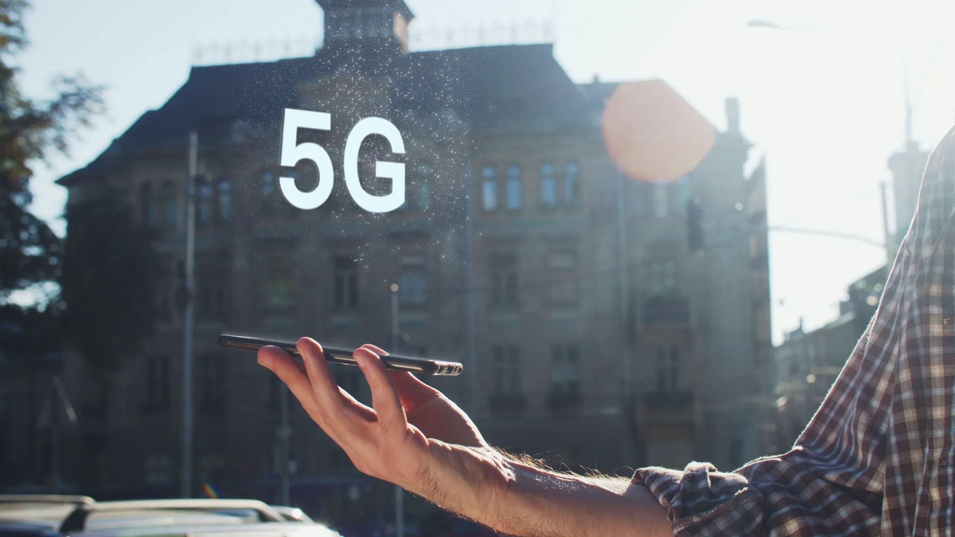 5G coming out of a phone in front of a building in broad daylight