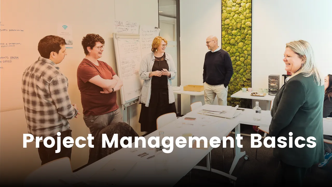 A group of people in a meeting room discussing project management, with a whiteboard and a moss wall in the background.