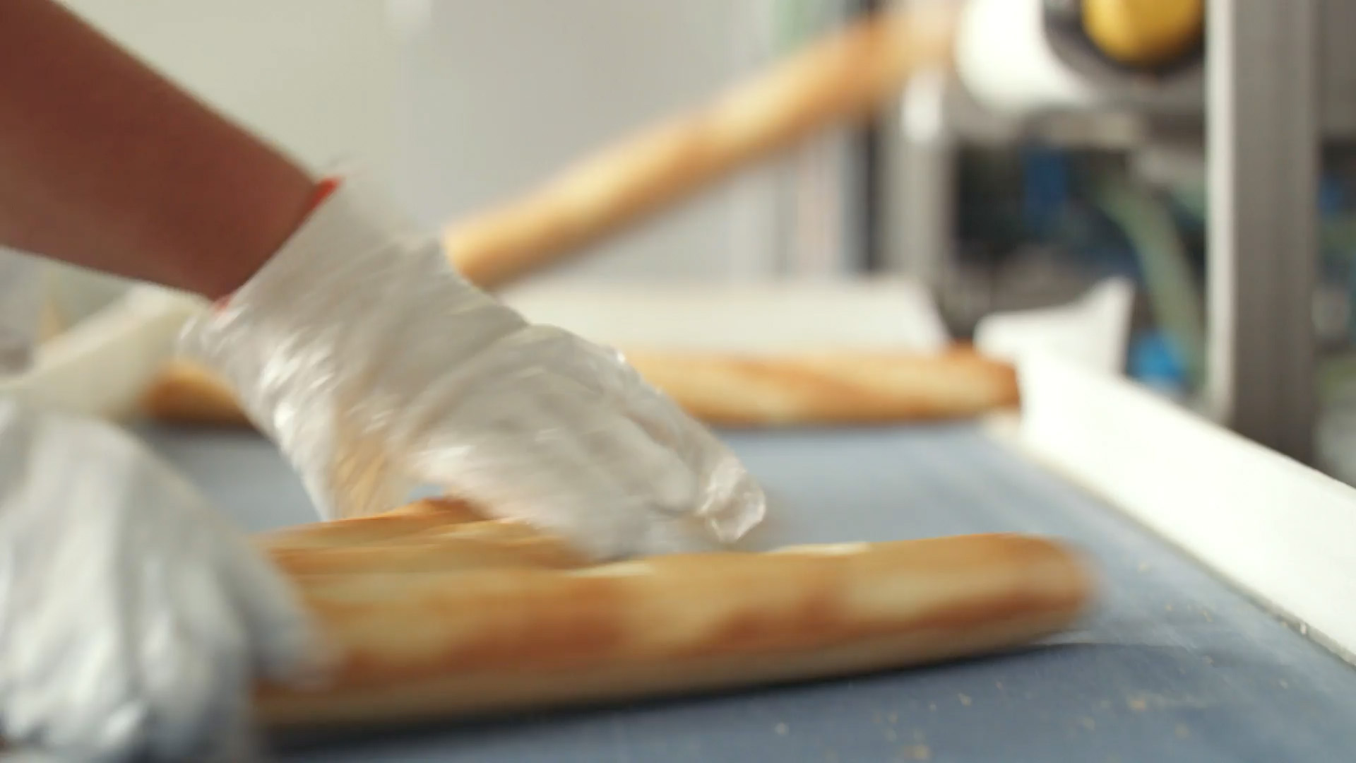Arranging baguettes on a conveyor belt in a bakery setting.