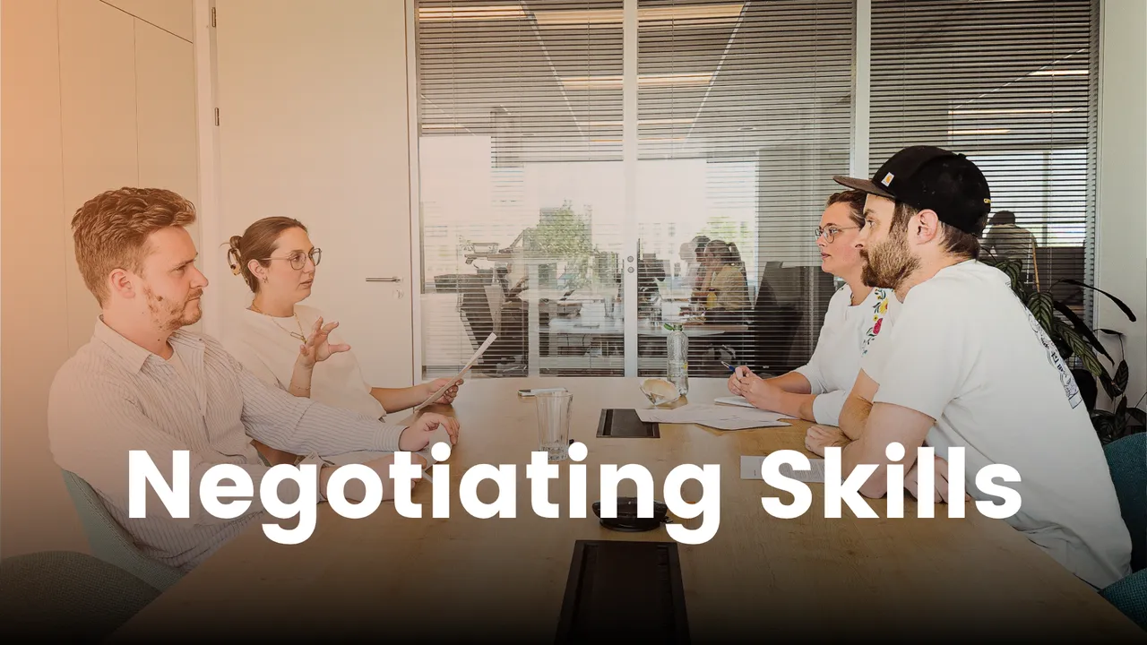 Four people in a meeting room engaged in discussion, with the text "Negotiating Skills" overlaid on the image.