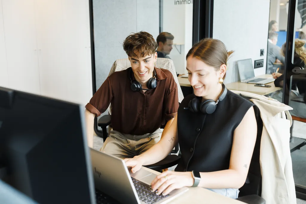 Man and woman sitting in front of computer at desk smiling