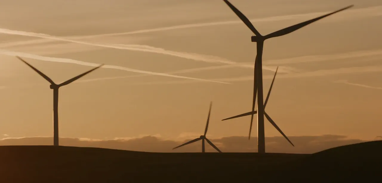 Wind turbines silhouetted against a vibrant sunset, showcasing renewable energy in harmony with nature's beauty.