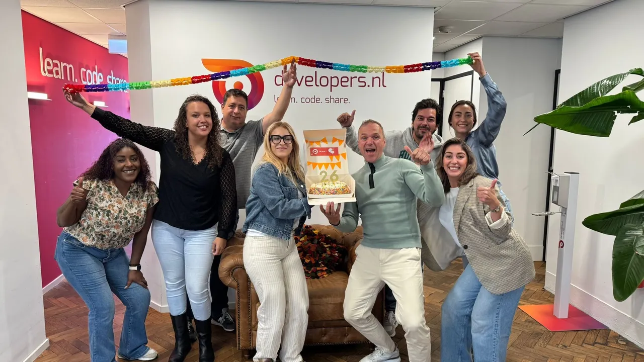 een groep mensen die enthousiast kijkt naar de camera met een taart in het midden