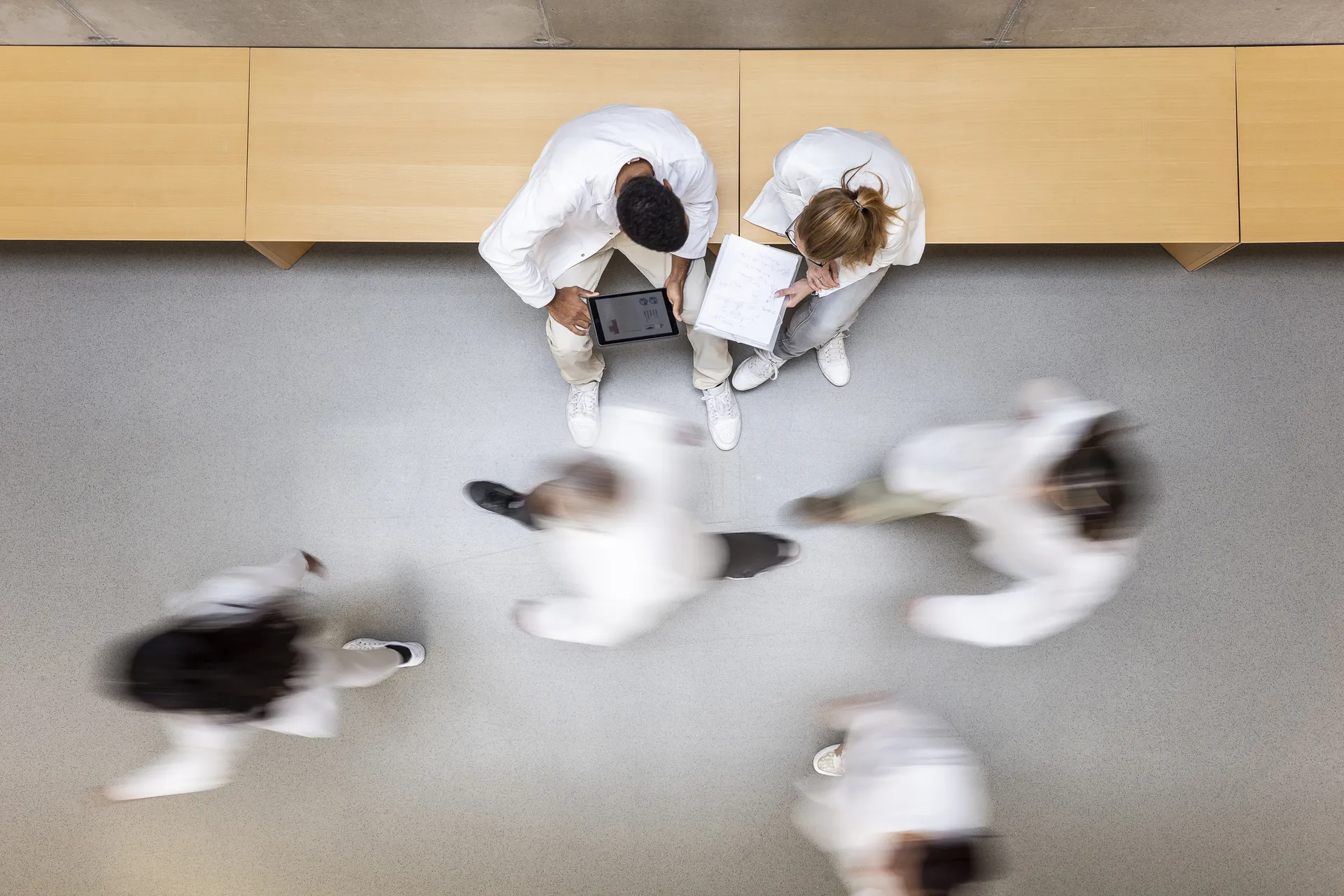 Scientists in lab attire are walking past each other