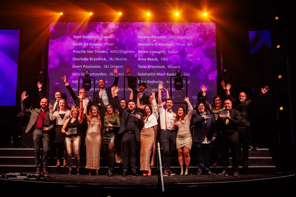 A diverse group of individuals on stage, enthusiastically raising their hands in celebration or support.
