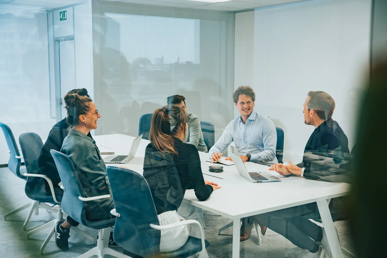 Several colleagues having a business meeting at their desk in Antwerp Office
