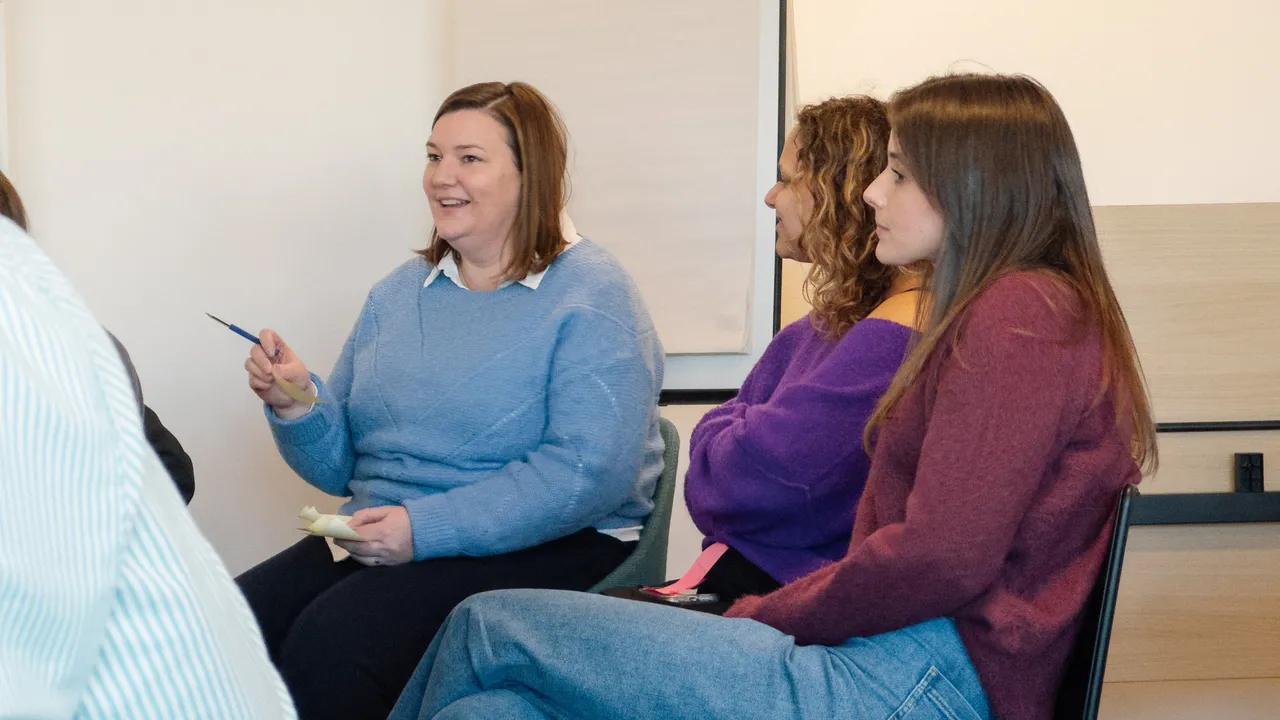 A group of individuals engaged in conversation while seated in a room.