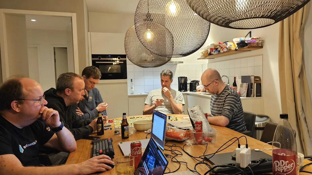 Groepn mannen zitten aan tafel met een laptop