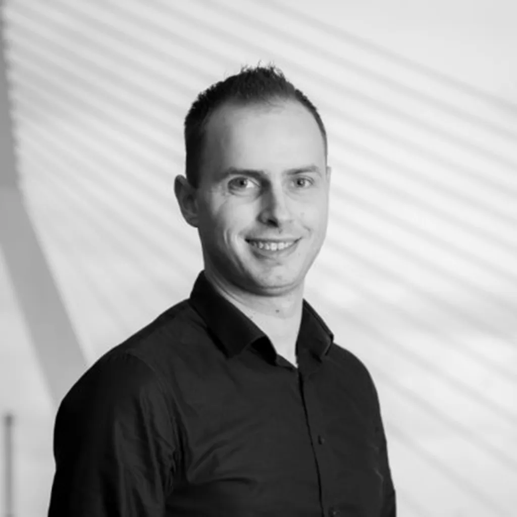 Black and white picture with a man smiling in a black blouse
