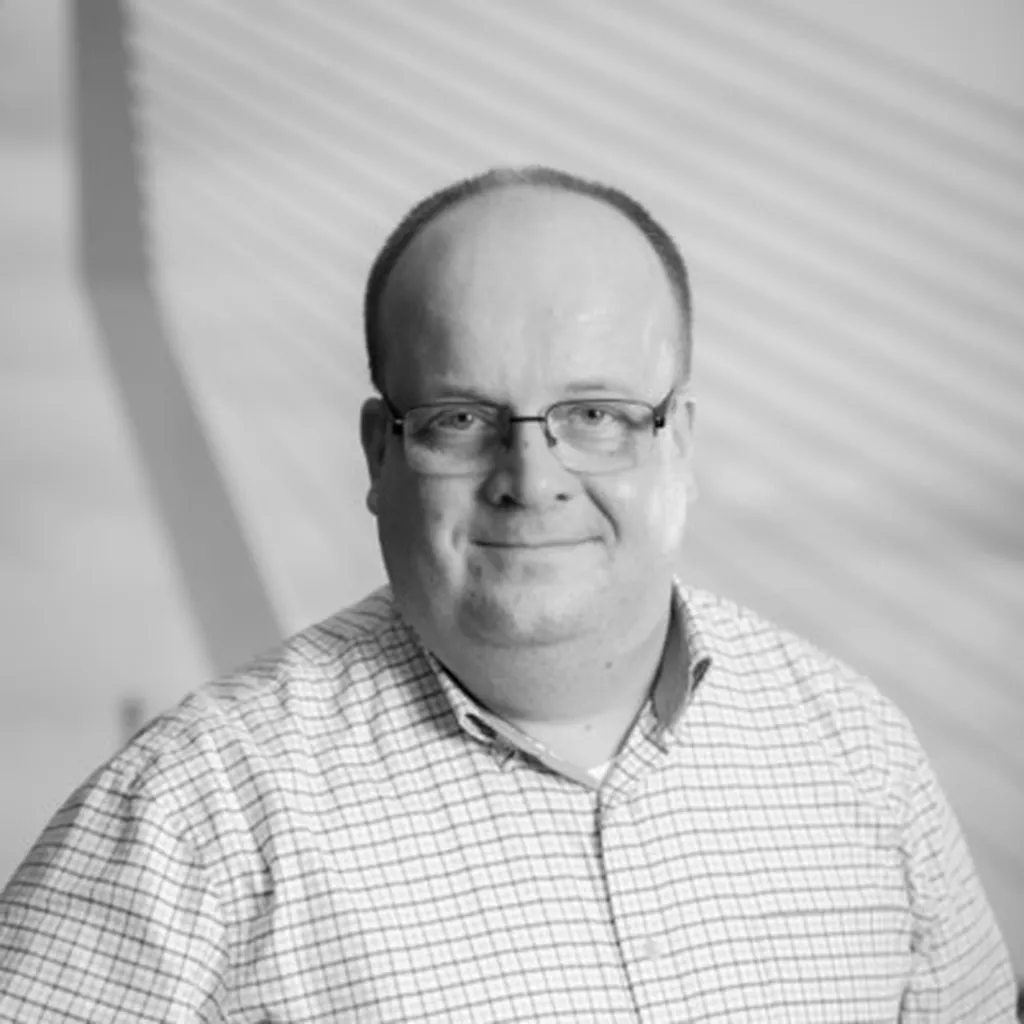 Black and white picture with a man smiling in a white blouse