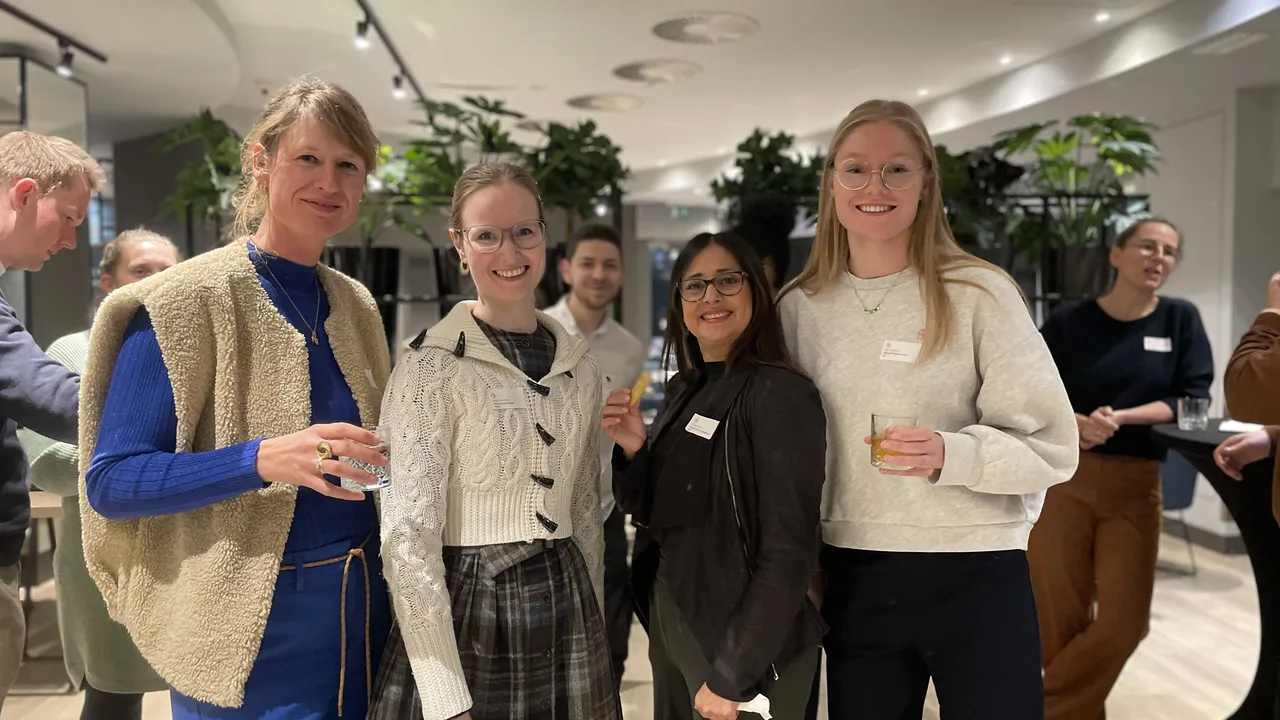 A group of women joyfully standing together, smiling and socializing at a lively party.