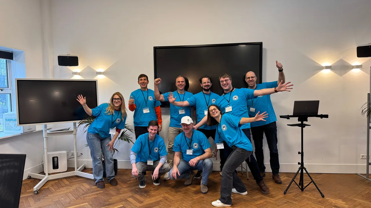 een groep mensen die enthousiast kijkt naar de camera met allemaal blauwe shirts aan voor devoxx4kids