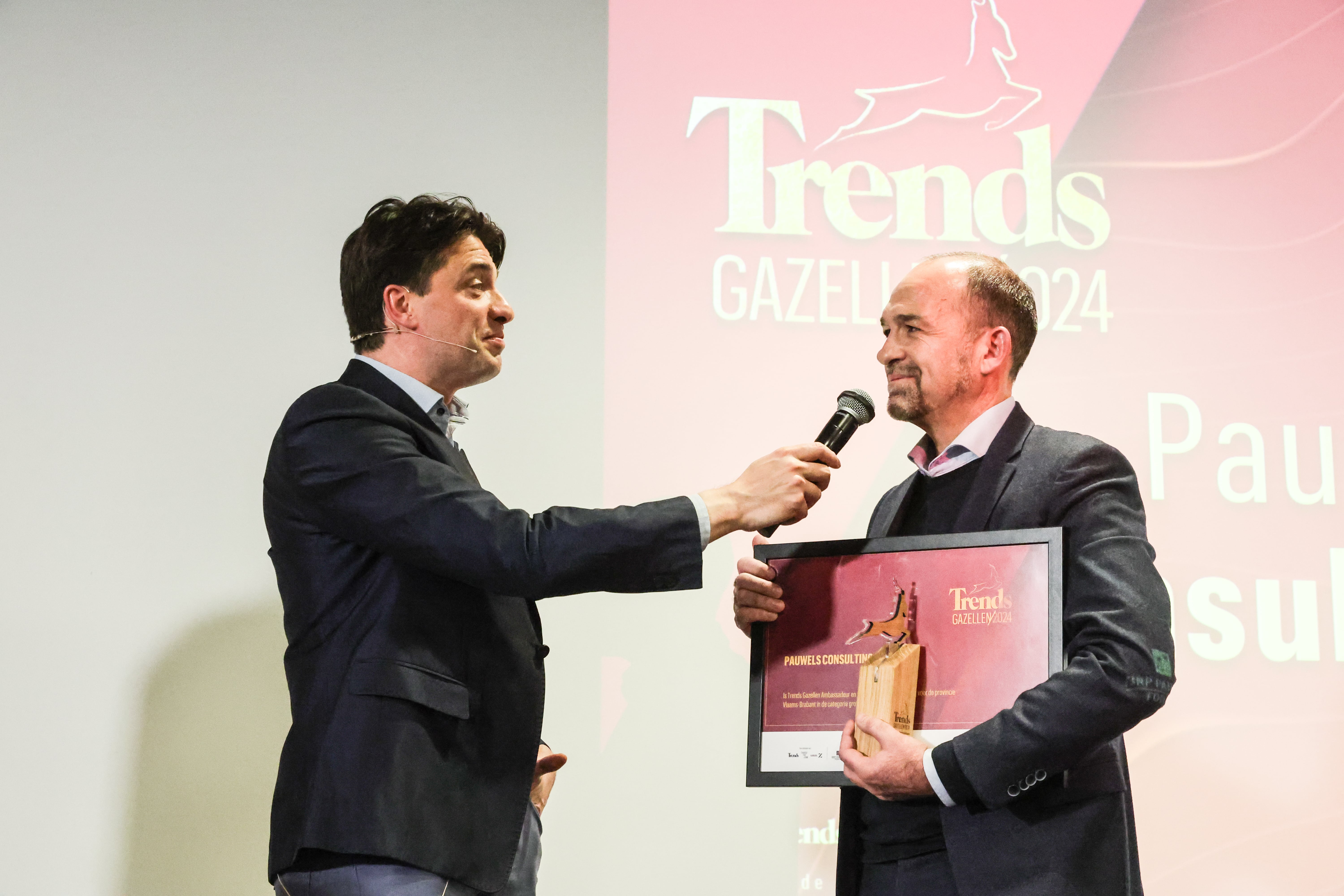 Two men proudly hold an award during a formal presentation, showcasing their achievement and recognition.