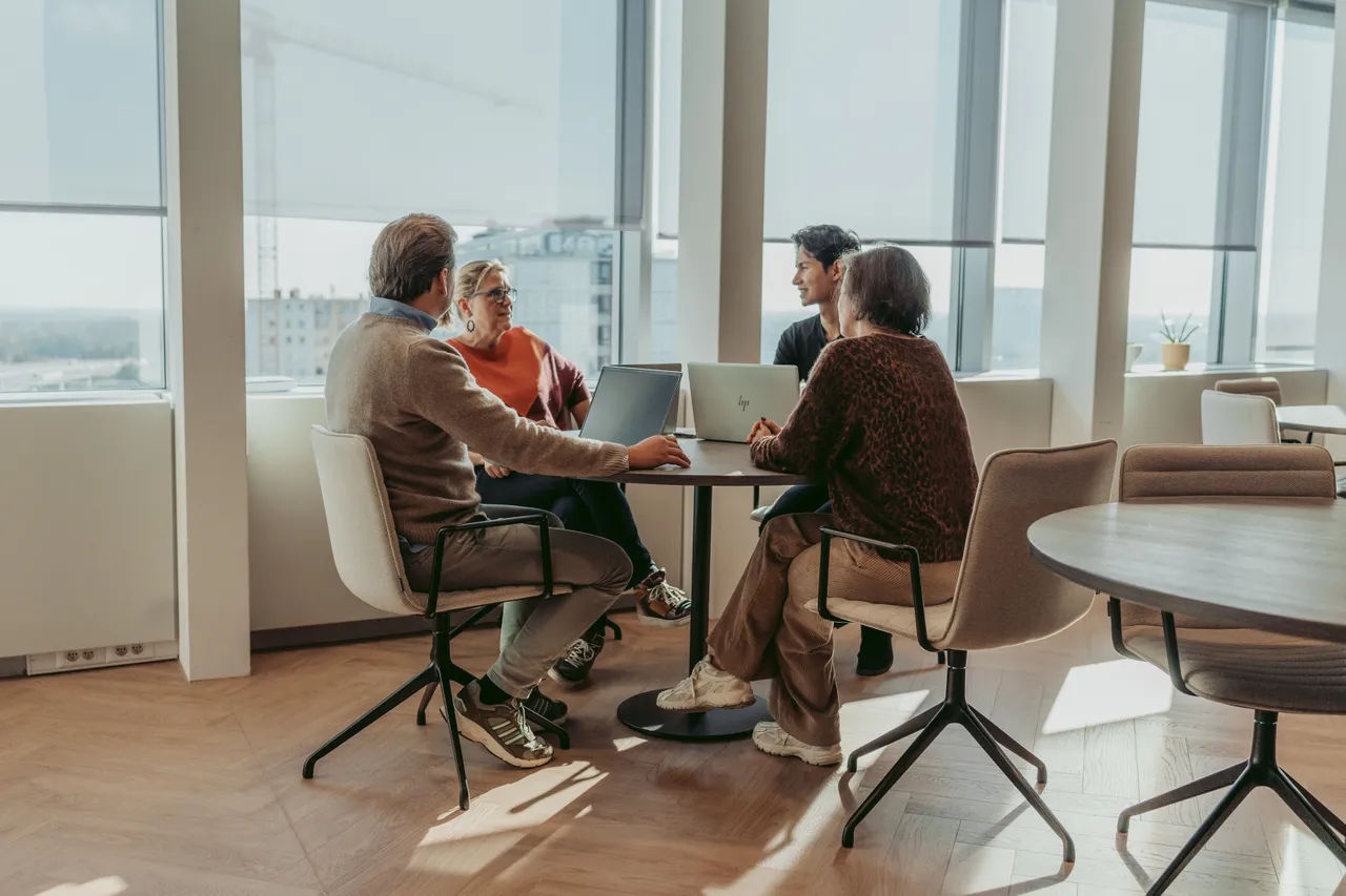 4 colleagues sitting at a round table in our Ghent Office and talking