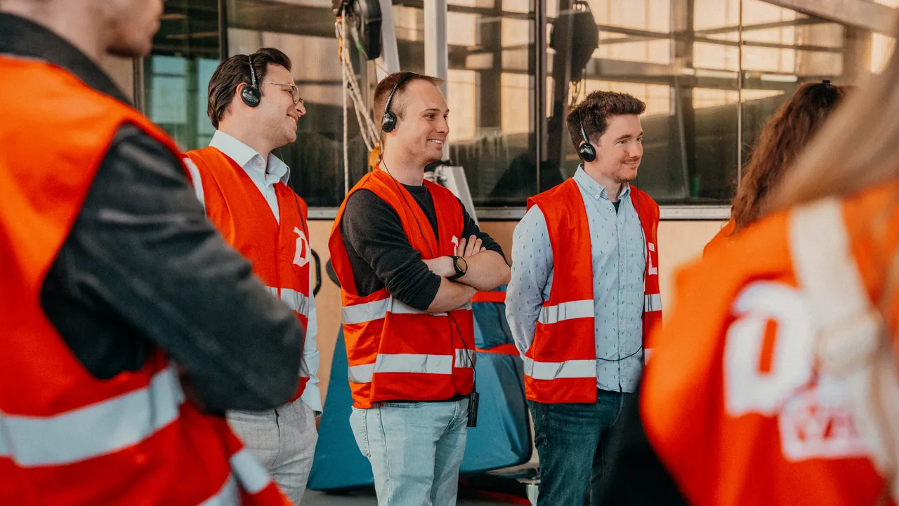 A group of individuals in orange vests and headphones, engaged in an activity, showcasing teamwork and communication.