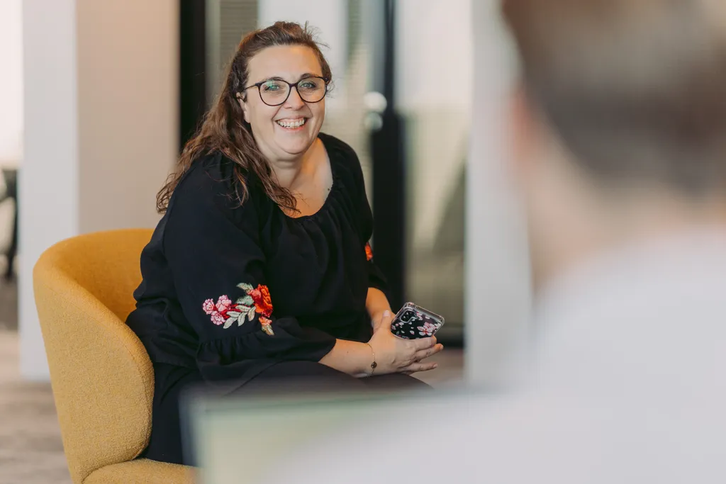 Woman sitting in chair whilst in conversation and smiling