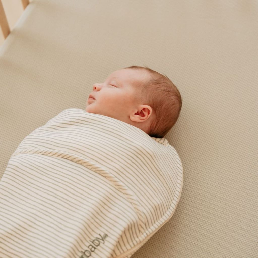 Een baby slaapt vredig op een geperforeerd AeroSleep-hoeslaken.