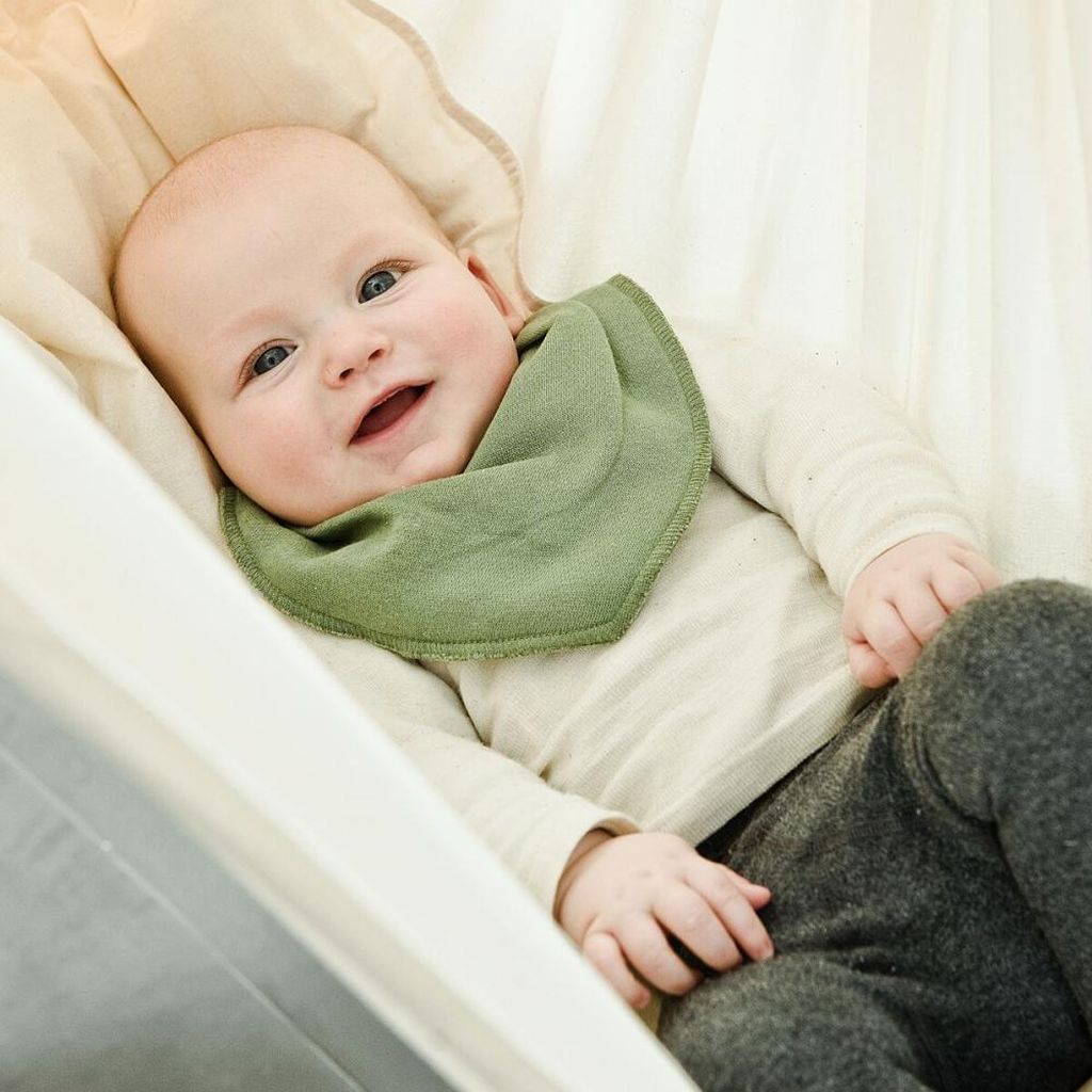 Baby lächelt in der 1.0 NONOMO Federwiege in Naturfarbe