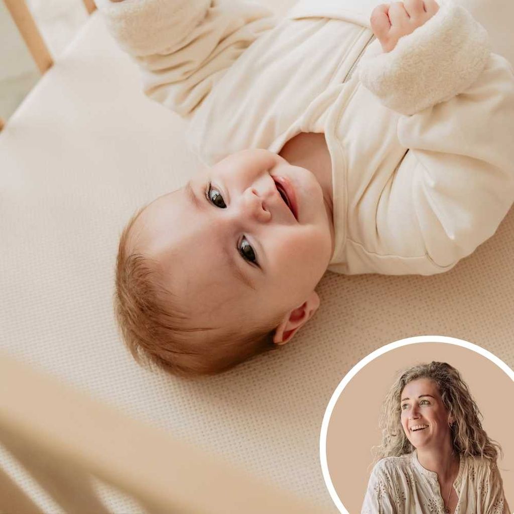 Vrolijke baby in een wieg met een cirkelvormige foto van een glimlachende vrouw.