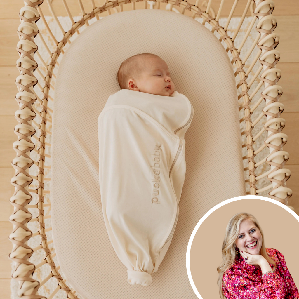 Un bébé endormi, vêtu d'une douce gigoteuse couleur crème, allongé sur un drap-housse AeroSleep dans un berceau tressé posé sur un parquet en bois clair.