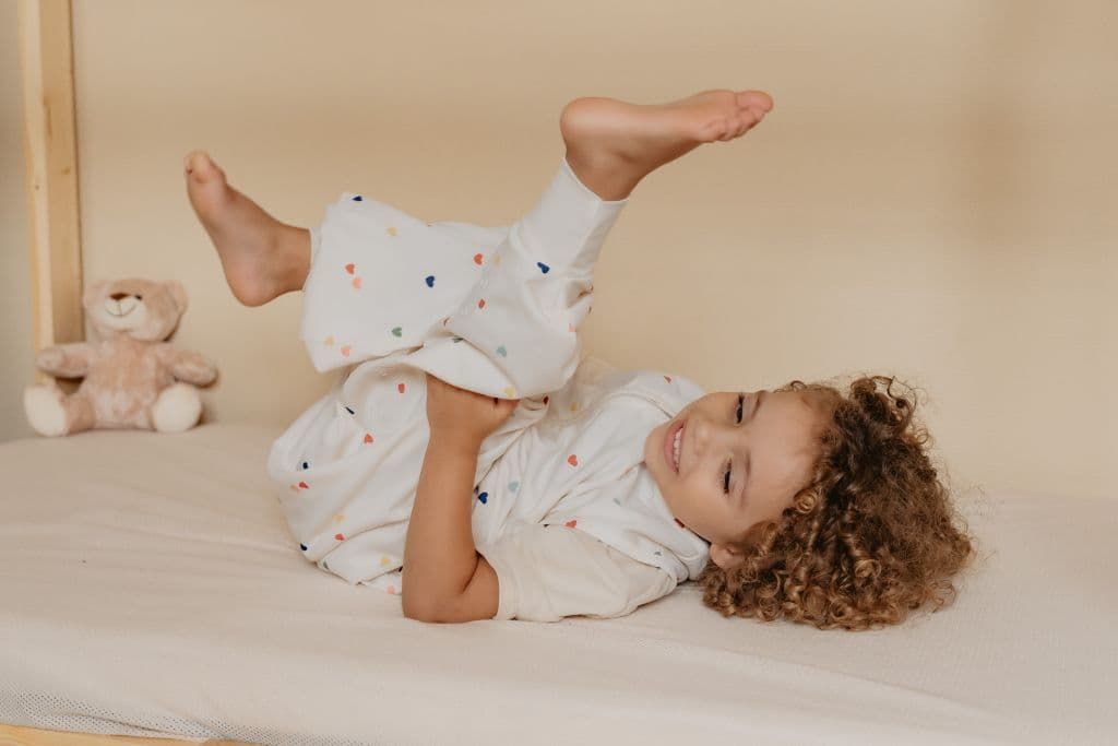 Toddler laying in bed wearing a sleeping bag