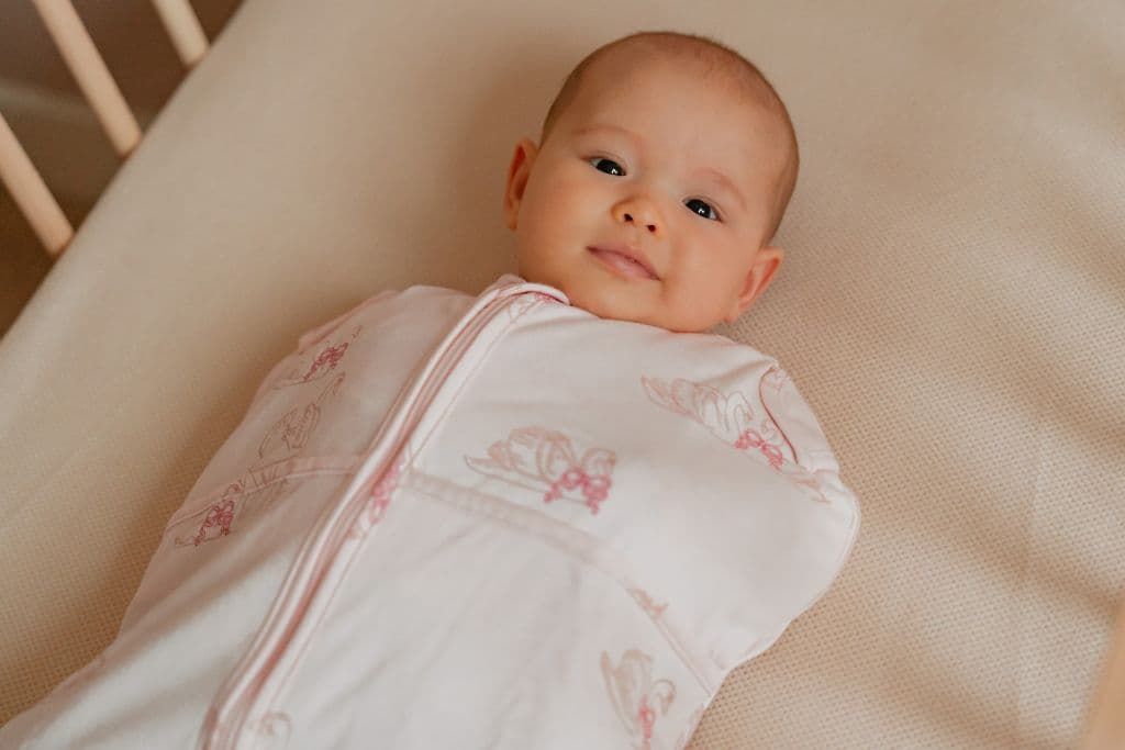 Baby laying in bed wearing a swaddle bag