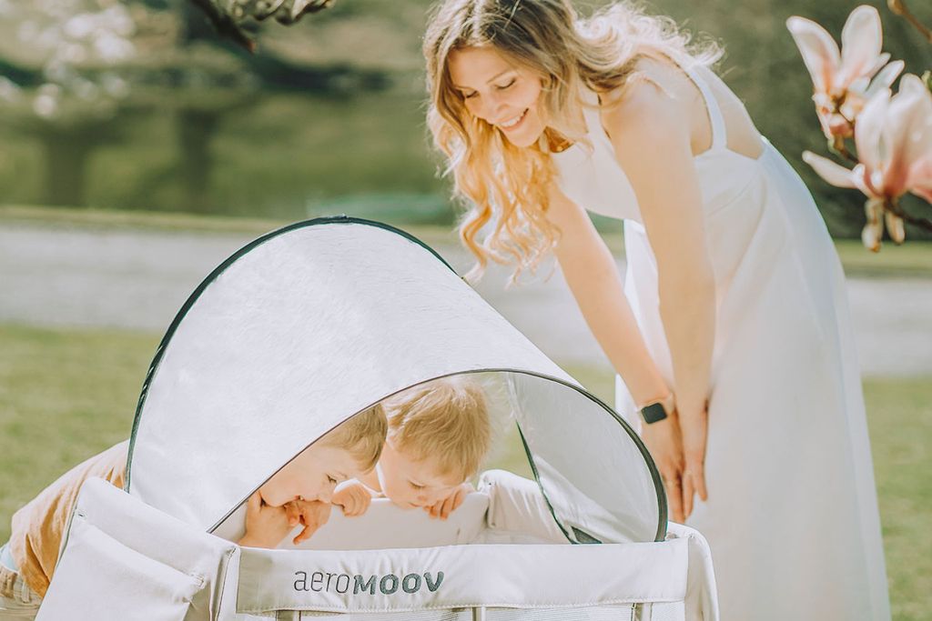 A instant travel cot with a sunshade attached in the sun