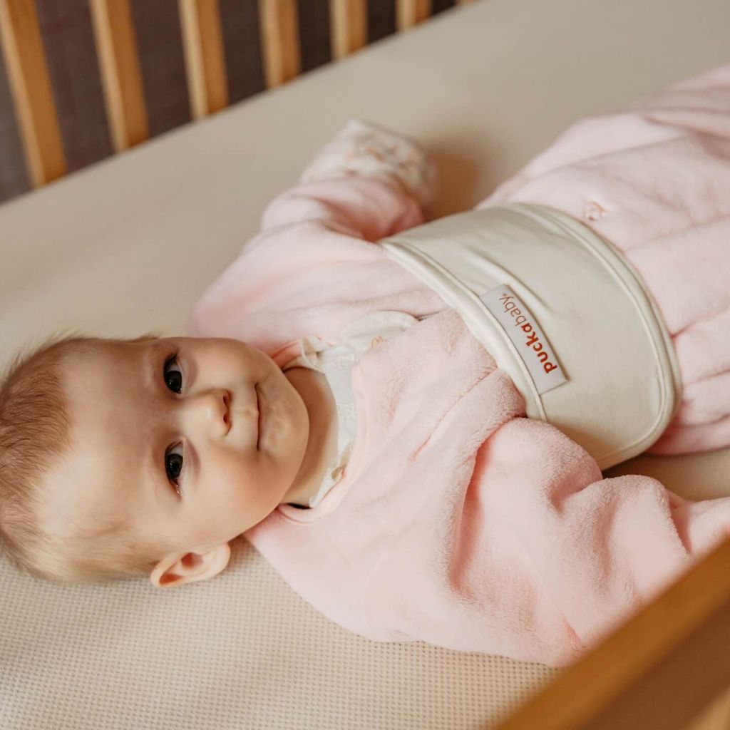 Baby in een slaapzak, omwikkeld met een Puckababy-buikband