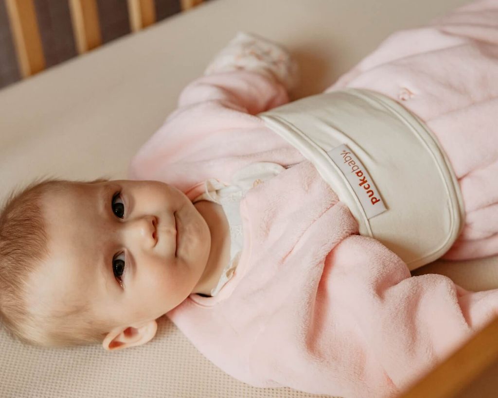 Bébé dans un sac de couchage, enveloppé dans une bande ventrale Puckababy