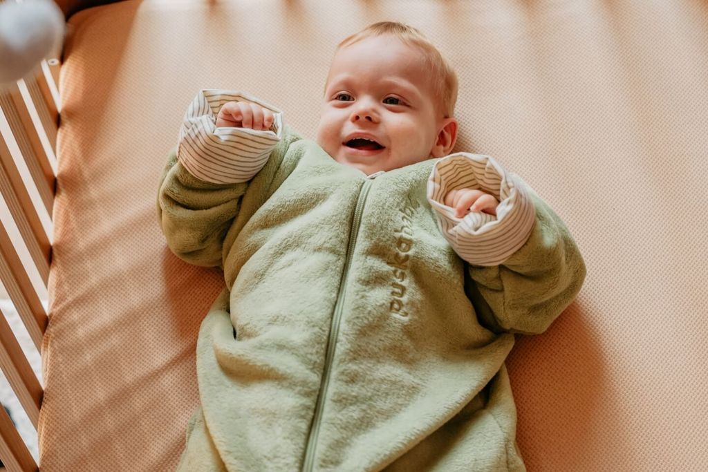 Blije baby in een slaapzak voor twee seizoenen (winter)