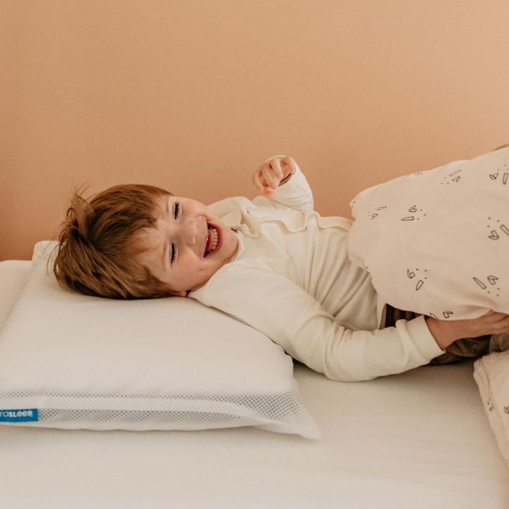 Een kindje ligt in bed op een AeroSleep-kussen en -hoeslaken.
