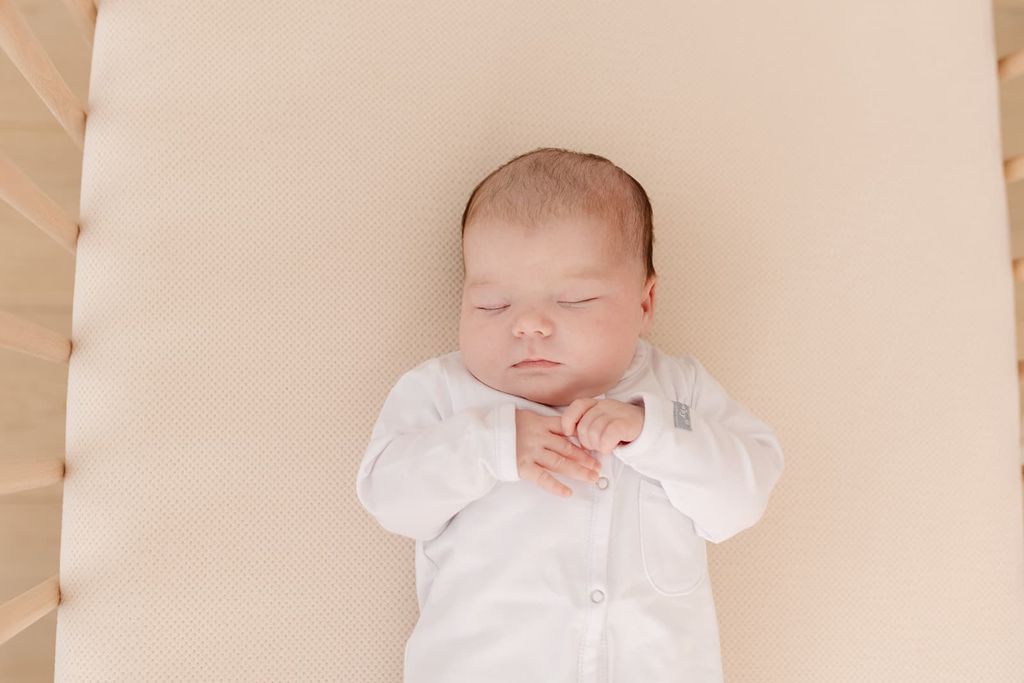Een baby slaapt vredig op een geperforeerd AeroSleep-hoeslaken