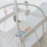 Glückliches Baby liegt in seinem Reisebett