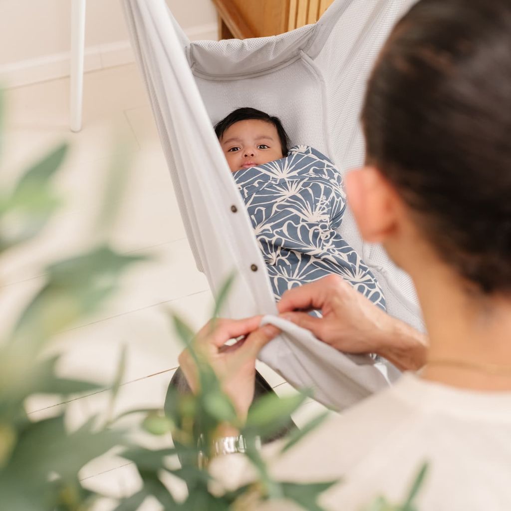 Baby in einem Wickelsack liegt in der Babyhängematte