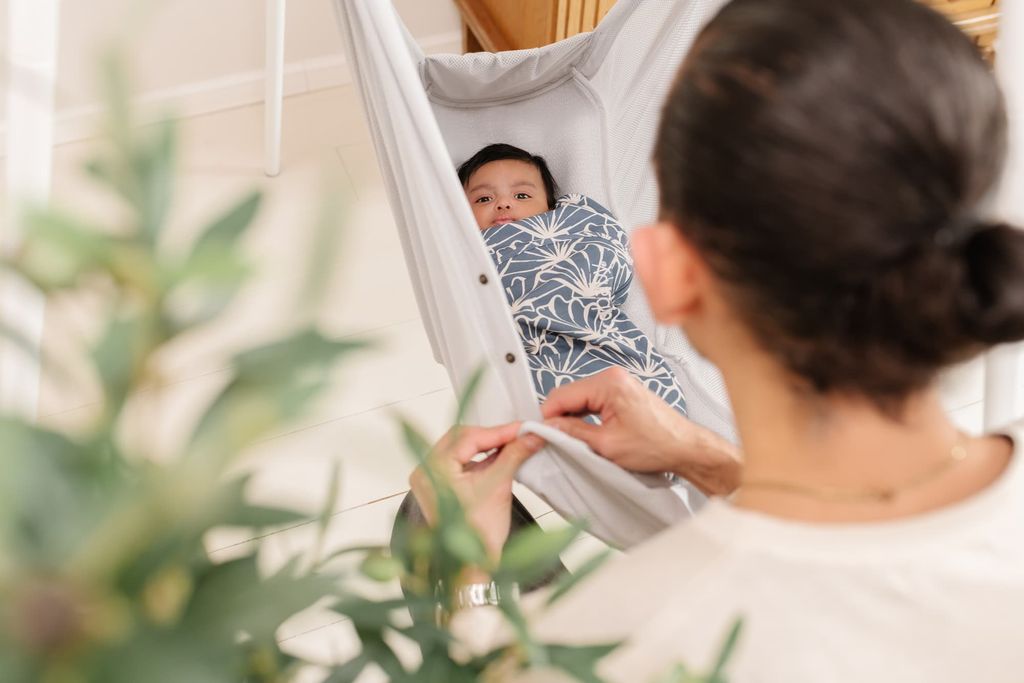 Baby in einem Wickelsack liegt in der Babyhängematte