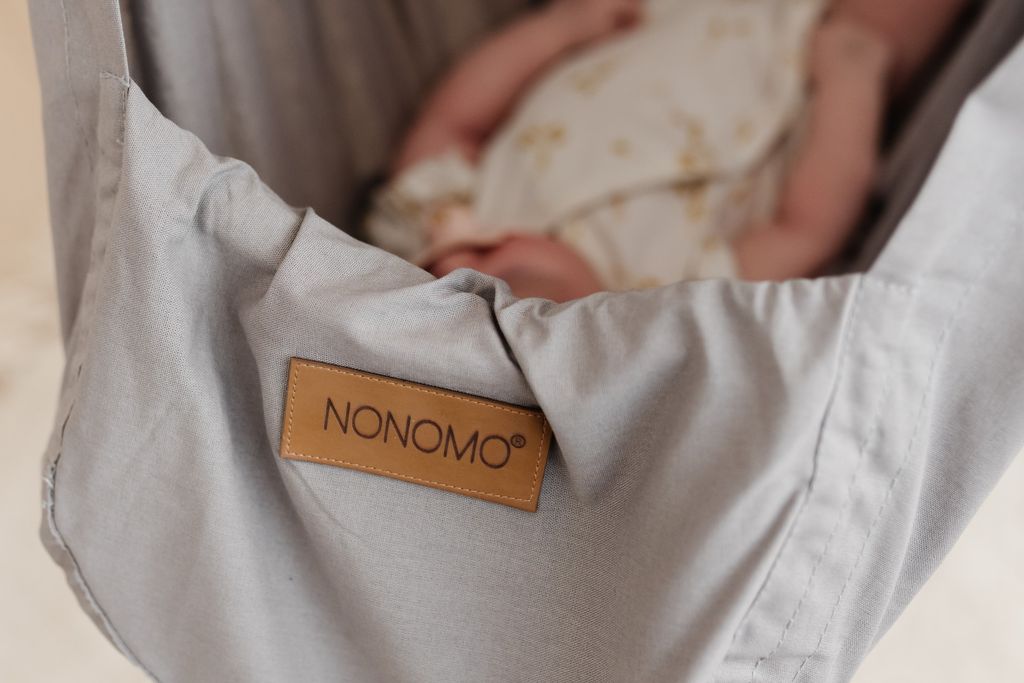 Nahaufnahme des Logos auf einer NONOMO Federwiege1.0 in grau