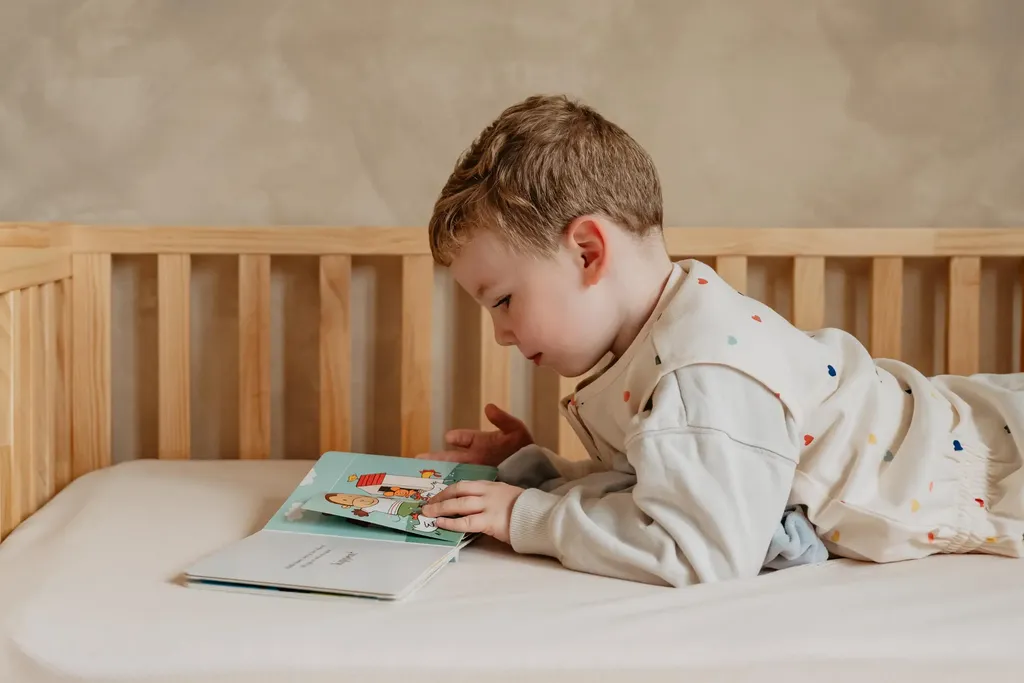 Een peuter ligt op een EvoDuo Junior-matras en leest rustig een boekje.